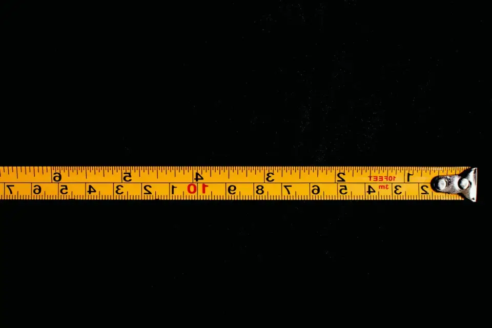 A person holding a tape measure against a dog&#x27;s back to determine crate size